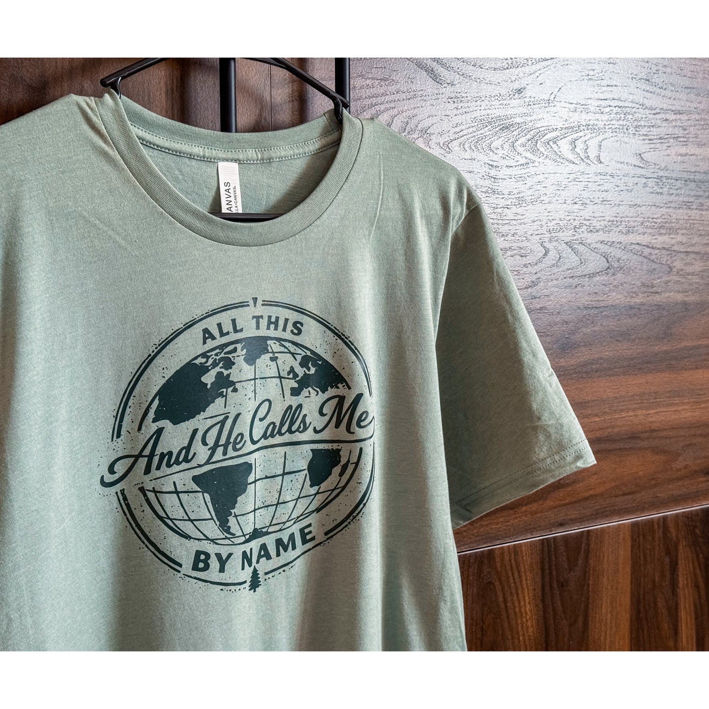 Green t-shirt with a world map design and text on a wooden surface